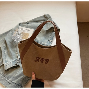 Detail of canvas tote bag featuring premium brown embroidery and durable woven handle
