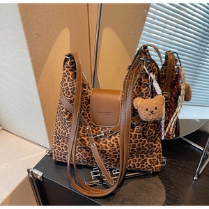 Detail of leopard print tote bag with brown leather straps and plush bear keychain