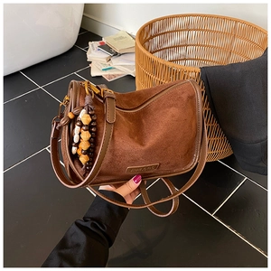 Detailed shot of brown suede crossbody bag with bohemian style beaded tassel and zipper