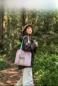 Outdoor model display of a pastel pink and green tote bag with mesh pocket on forest trail
