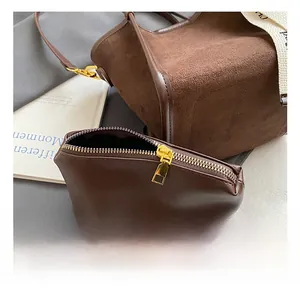 Détail du sac seau marron avec ferrures dorées et texture de la bandoulière jacquard