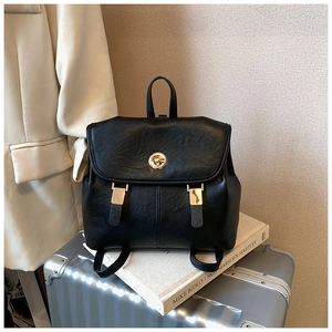 Detail of vintage black PU leather backpack with gold rotating lock and metal hardware