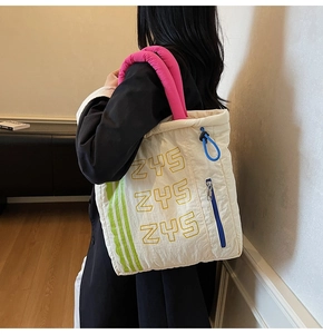 Detail of quilted canvas tote with magenta handles and blue drawstring pockets