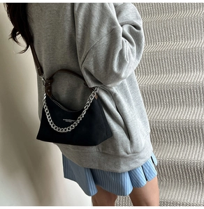 Mannequin portant un sac noir avec chaîne argentée et bandoulière marron sur un sweat