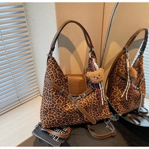 Detail view of leopard print tote bag with brown leather trim and bear pendant charm