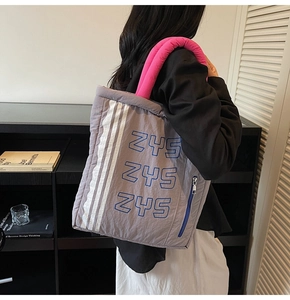 Detailed macro view of quilted nylon tote bag with pink handles and side zipper pocket