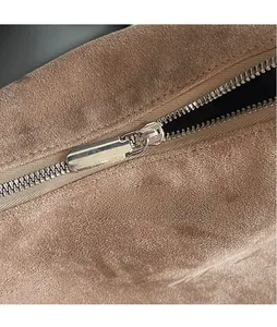Détail de la fermeture éclair en métal argenté sur un sac fourre-tout en daim brun