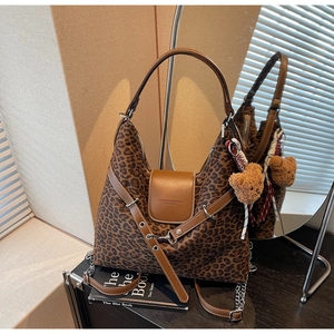 Detail of leopard print tote bag with brown leather flap and cute plush bear charm