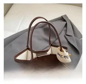 Détail du sac seau en daim marron foncé avec bordure en cuir et ruban logo tissé
