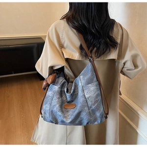 Close-up of blue denim canvas tote bag with brown leather labels and dual straps