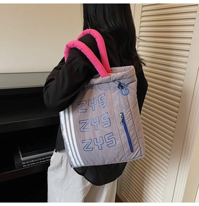 Detail of grey quilted tote bag with pink handles and blue ZYS logo with white stripes