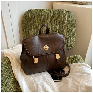 Close-up of vintage dark brown leather backpack with gold twist lock and flap design