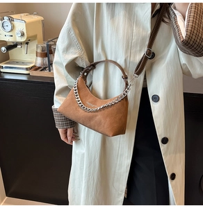 Détail du sac hobo en daim marron avec une grosse chaîne argentée et bandoulière en cuir
