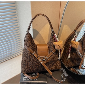 Detail shot of leopard print tote bag with brown leather trim and plush bear charm