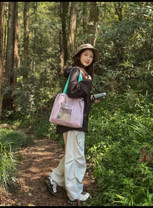 Detail of light purple drawstring tote with blue strap in an outdoor forest hiking scene