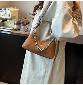 Détail du sac demi-lune en daim marron avec chaîne argentée et logo texte blanc