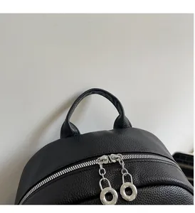Detail of black lychee grain leather backpack with dual silver zippers and top handle
