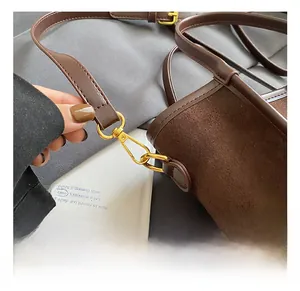 Gros plan du crochet en métal doré sur un sac seau en daim marron foncé élégant