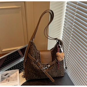 Detail of leopard print tote bag with brown leather flap and plush bear charm