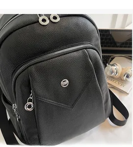 Detailed view of black pebbled leather backpack with silver zippers and metal logo