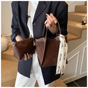 Détail d'un sac seau en daim marron avec ruban décoratif et pochette assortie