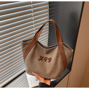 Detail of khaki canvas tote bag featuring brown HOG embroidery and durable wide straps