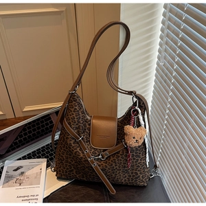 Close-up of leopard print hobo bag with leather strap and cute bear charm detail