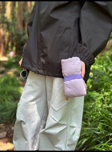 Close-up of lightweight lilac outdoor tote bag being stowed away by a hiker in the woods
