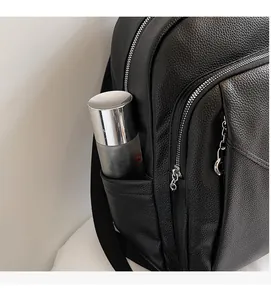 Detail of black pebbled leather backpack side pocket with silver zipper and chain