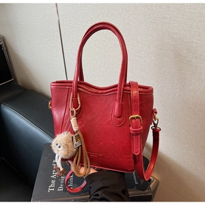 Dettaglio della borsa tote in pelle rossa con ciondolo di peluche e tracolla regolabile