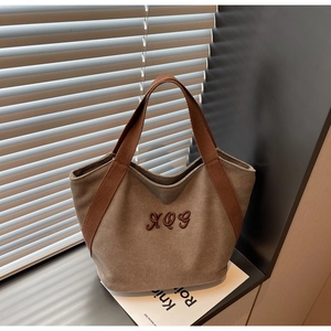 Detail view of khaki canvas tote bag with XQG embroidery and brown woven handle