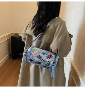 Dettaglio borsa a cilindro in denim con toppe colorate e tracolla larga