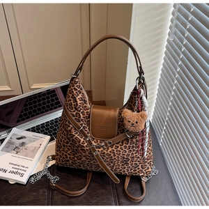 Macro detail of leopard print tote bag with brown leather flap and teddy bear charm