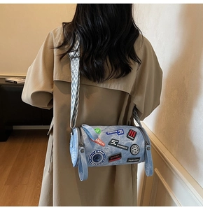 Dettaglio della borsa a cilindro in denim con toppe colorate e tracolla geometrica
