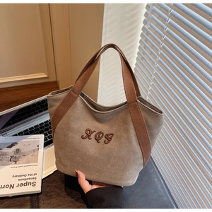 Close-up of khaki canvas tote bag featuring brown RQG embroidery and thick handles