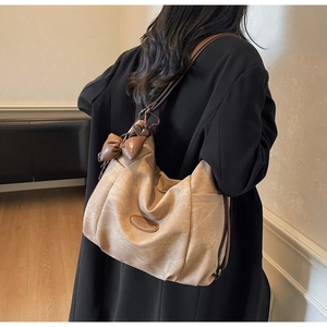 Model view of a large khaki tote bag with a bow charm and heart pendant detail