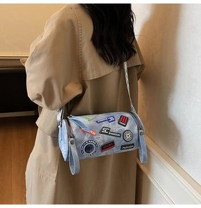 Vista dettagliata della borsa a tracolla cilindrica in denim blu con ricami street style