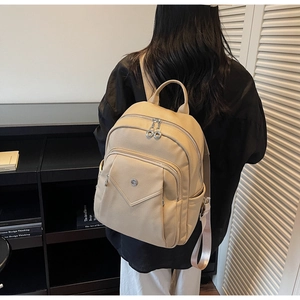 Detail view of cream textured leather backpack with silver zippers and side pockets
