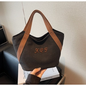 Detail view of the black canvas tote bag featuring embroidered XOG logo and brown handles