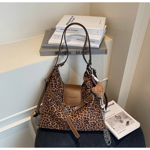 Detailed close-up of leopard print tote bag with brown leather accents and bear charm