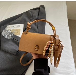 Detail of camel brown crossbody bag with unique knotted handle and colorful bead tassel