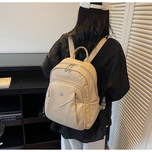 Beige faux leather backpack shown on a model in a stylish study room setting