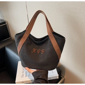 Detailed close-up of a canvas tote bag with brown straps and XOG embroidery