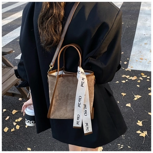 Sac seau chic en daim marron avec anses en cuir et détail de ruban à logo élégant