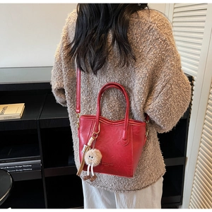 Vista dettagliata di una borsa a secchiello vintage bordeaux con charm in peluche