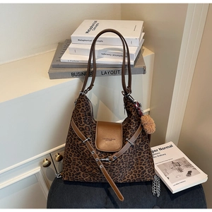 Detailed view of leopard print hobo bag featuring brown leather straps and plush charm