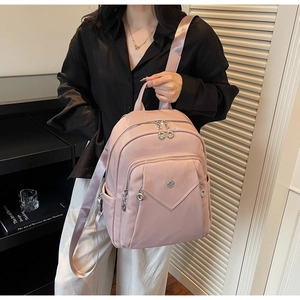 Detail view of light pink lychee texture backpack with silver zippers on model back
