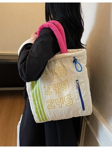Quilted tote bag with pink handles and ZYS print shown from a side view on model
