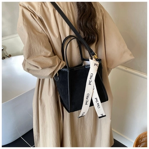 Détail du sac seau noir mat avec ruban décoratif porté par un mannequin