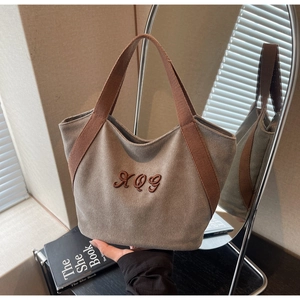 Detailed view of canvas tote bag with XQG embroidery and sturdy webbing handles
